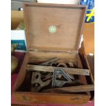 A wooden box containing a quantity of tools including micrometers, squares, etc.