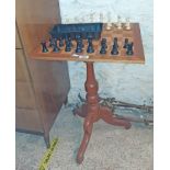 A reproduction mixed wood pedestal games tables with set of chessmen, set on turned pillar and