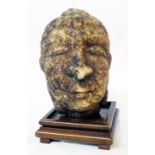 A carved crystalline stone head of a buddha on wooden plinth