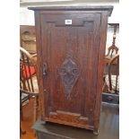 An 18" early 20th Century varnished oak cupboard enclosed by a decorative carved panel door
