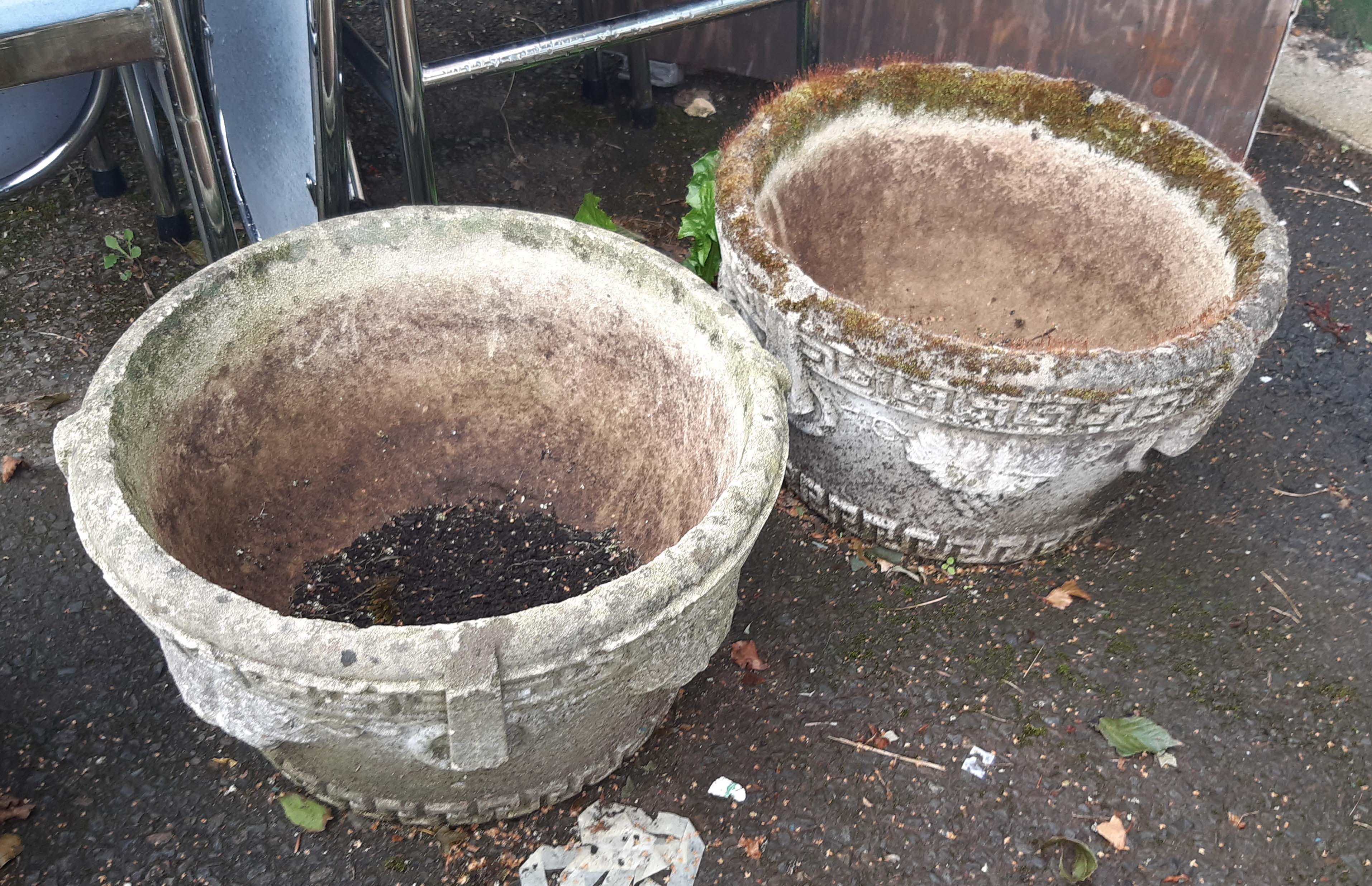 A pair of circular concrete garden planters with grapevine decoration