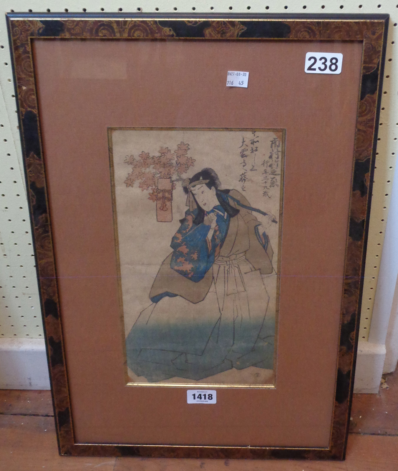 A lacquered framed Japanese wood block print, depicting a figure carrying a flowering branch with