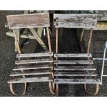 A pair of old wrought iron framed garden chairs with wooden slat seating
