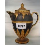 A Wedgwood black basalt hot water jug decorated in relief with Rococo swag and leaf motifs, with