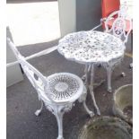 A vintage cast metal circular garden table with two chairs
