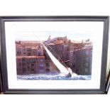 A large framed colour photograph, depicting a sailing boat with continental shore side buildings -