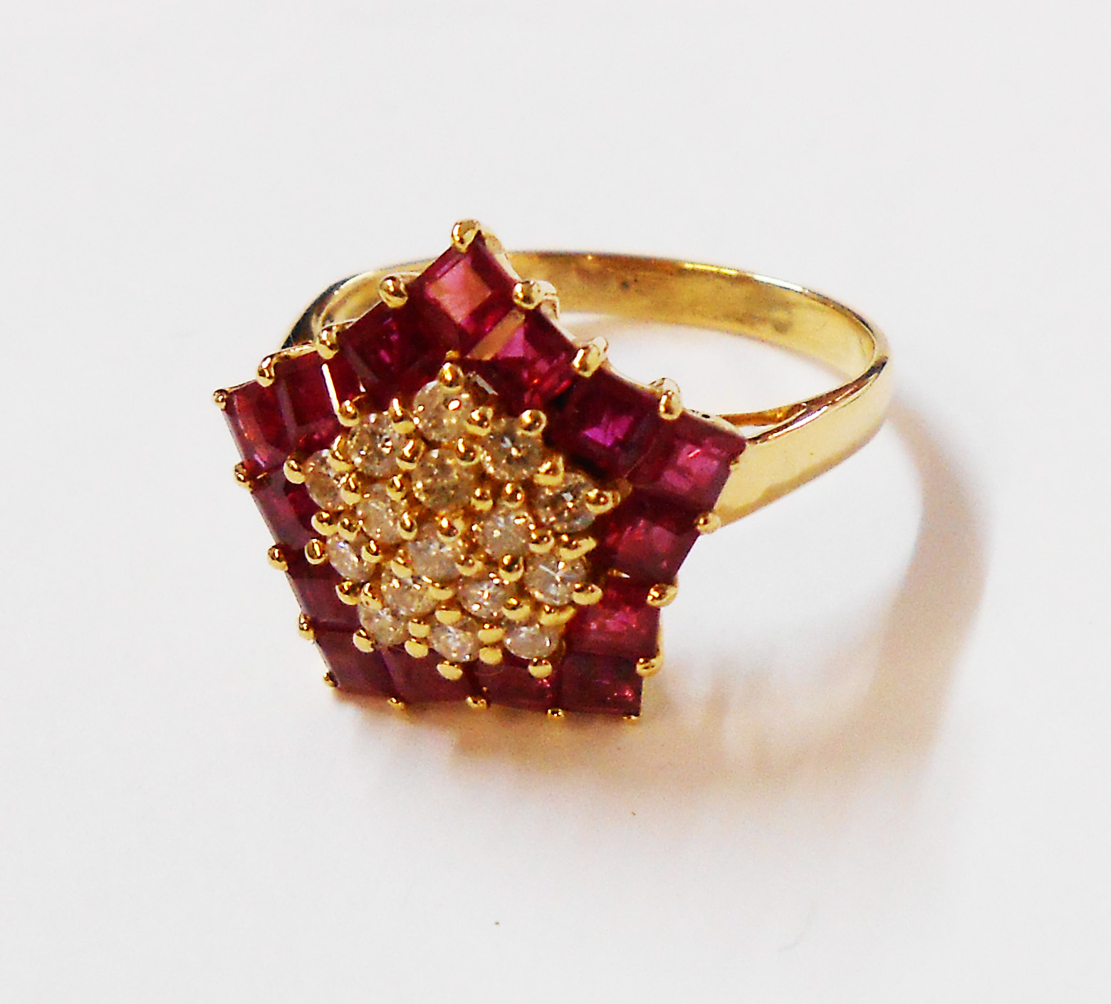 A marked 18K/750 yellow metal star pattern ring, set with diamond encrusted centre within a ruby
