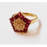 A marked 18K/750 yellow metal star pattern ring, set with diamond encrusted centre within a ruby