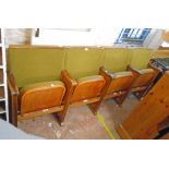 A row of four vintage cinema seats with polished wood part show frames, moulded arm rests and