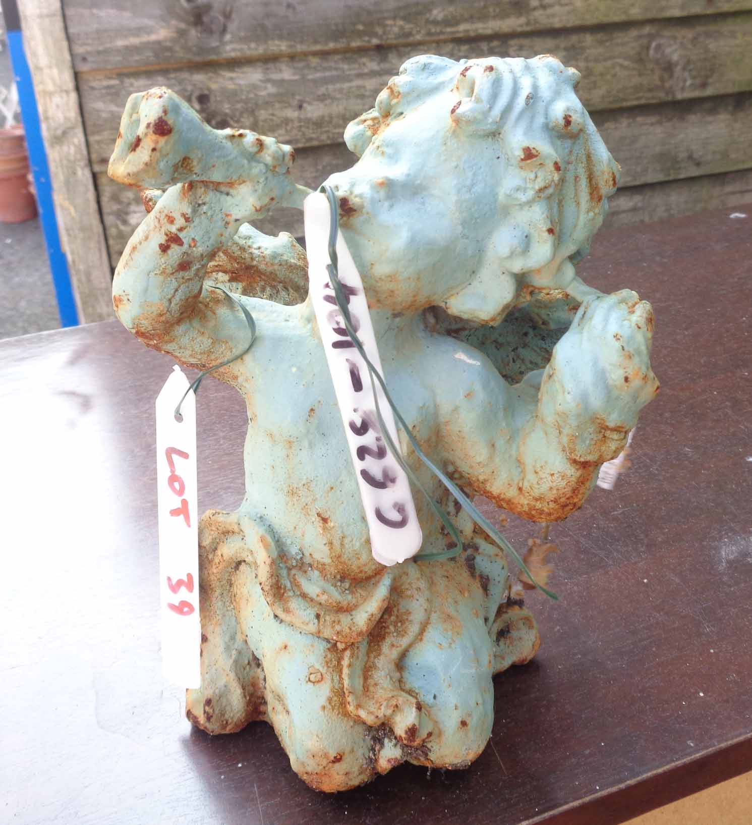 A small painted cast iron cherub with trumpet