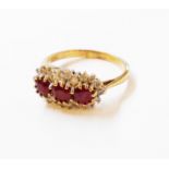 A marked 375 gold ring, set with three rubies within a shaped diamond encrusted border