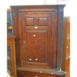 A 35" Georgian oak wall hanging corner cupboard with fluted canted sides, panelled door and later