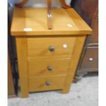 An 18" polished oak and mixed wood three drawer bedside chest, set on block feet