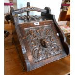 A Victorian heavily carved oak slope fronted coal box with floral and lion mask scroll decoration,