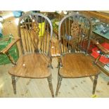 A pair of old wheel back elbow chairs with solid elm moulded seats, set on turned supports - for