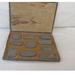 A cased set of ten early 20th Century Chinese ink cakes with bronzed decoration depicting Luohan -