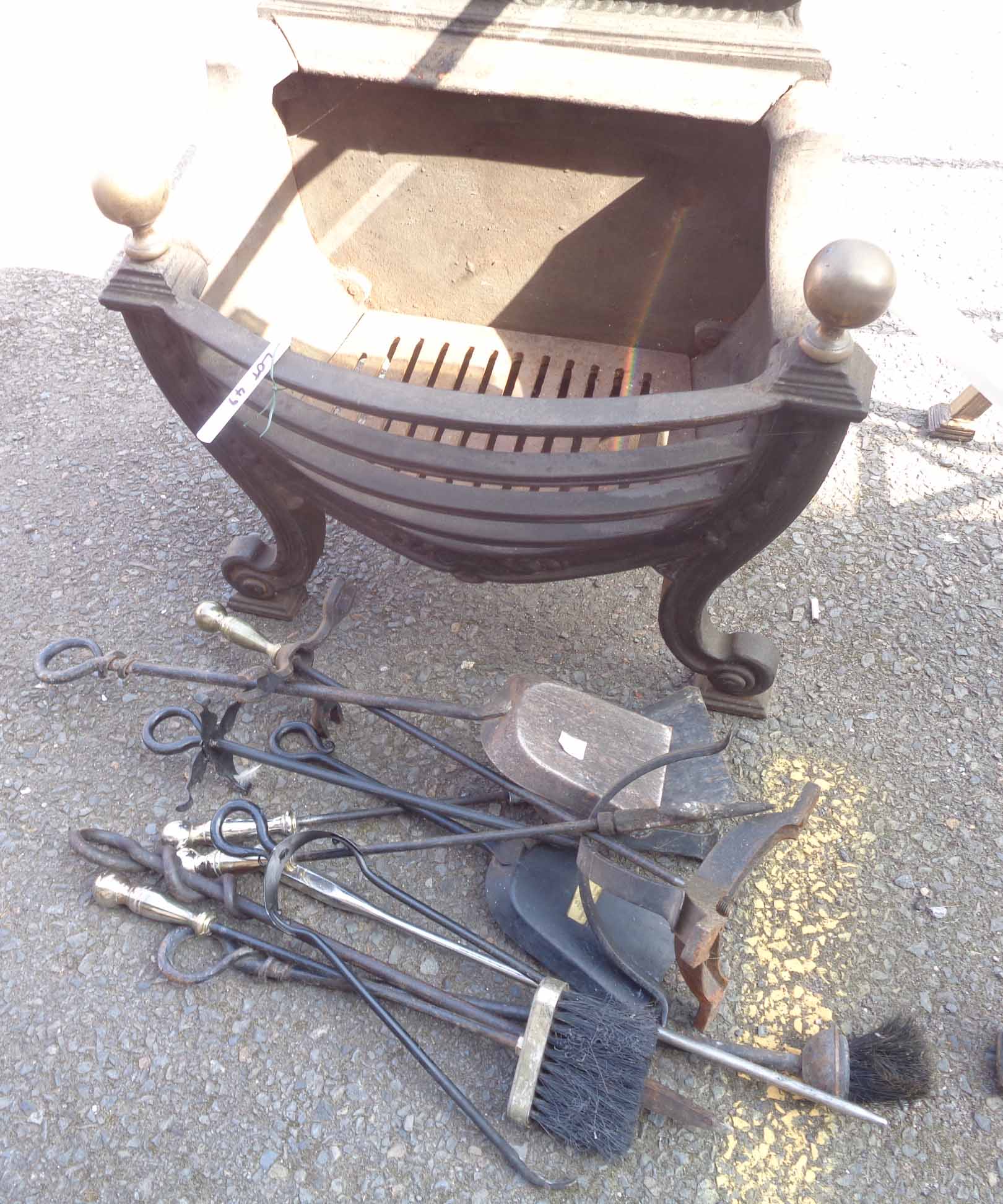 A large cast iron fire grate with brass finials, and various fire tools