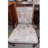 An Edwardian inlaid walnut framed nursing chair with spindle top rail and later upholstered back and