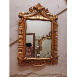 A 32" high giltwood framed wall mirror with decorative pierced floral scroll pediment and C-scroll