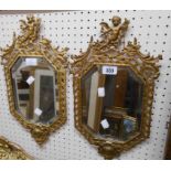 A pair of 17 1/4" old cast brass framed bevelled octagonal wall mirrors with cherubs to tops,