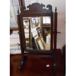 A small 19th Century mahogany framed swing mirror with fret-cut pediment and moulded supports -