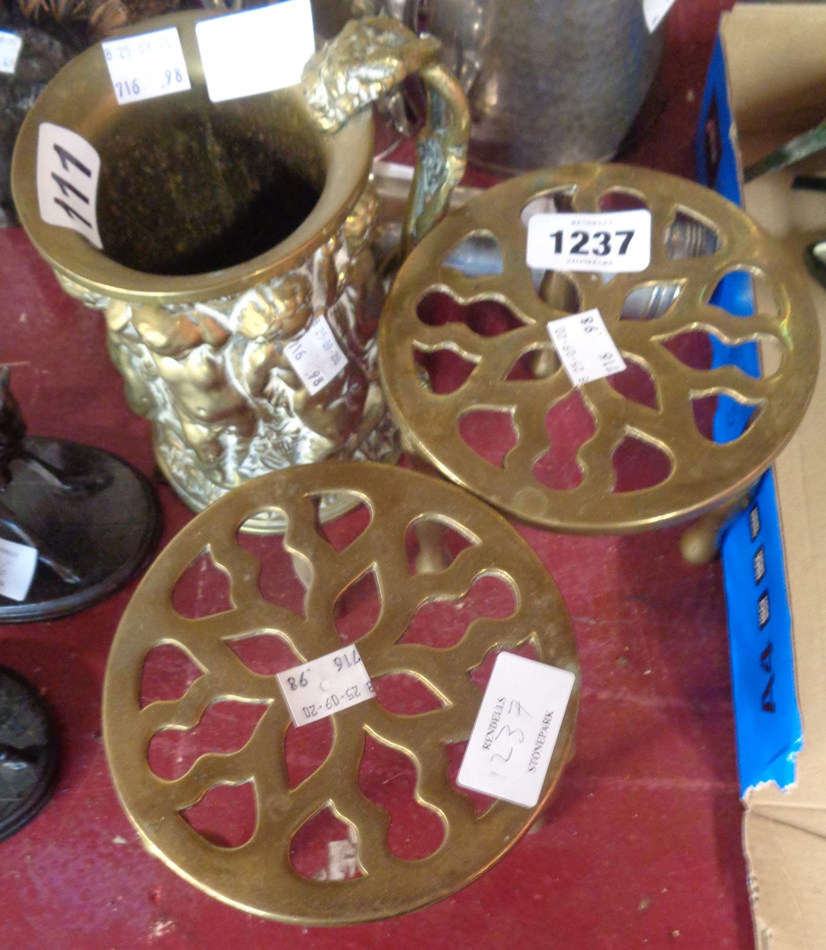 Two brass trivets and a brass tankard embossed with putti