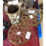 Two brass trivets and a brass tankard embossed with putti