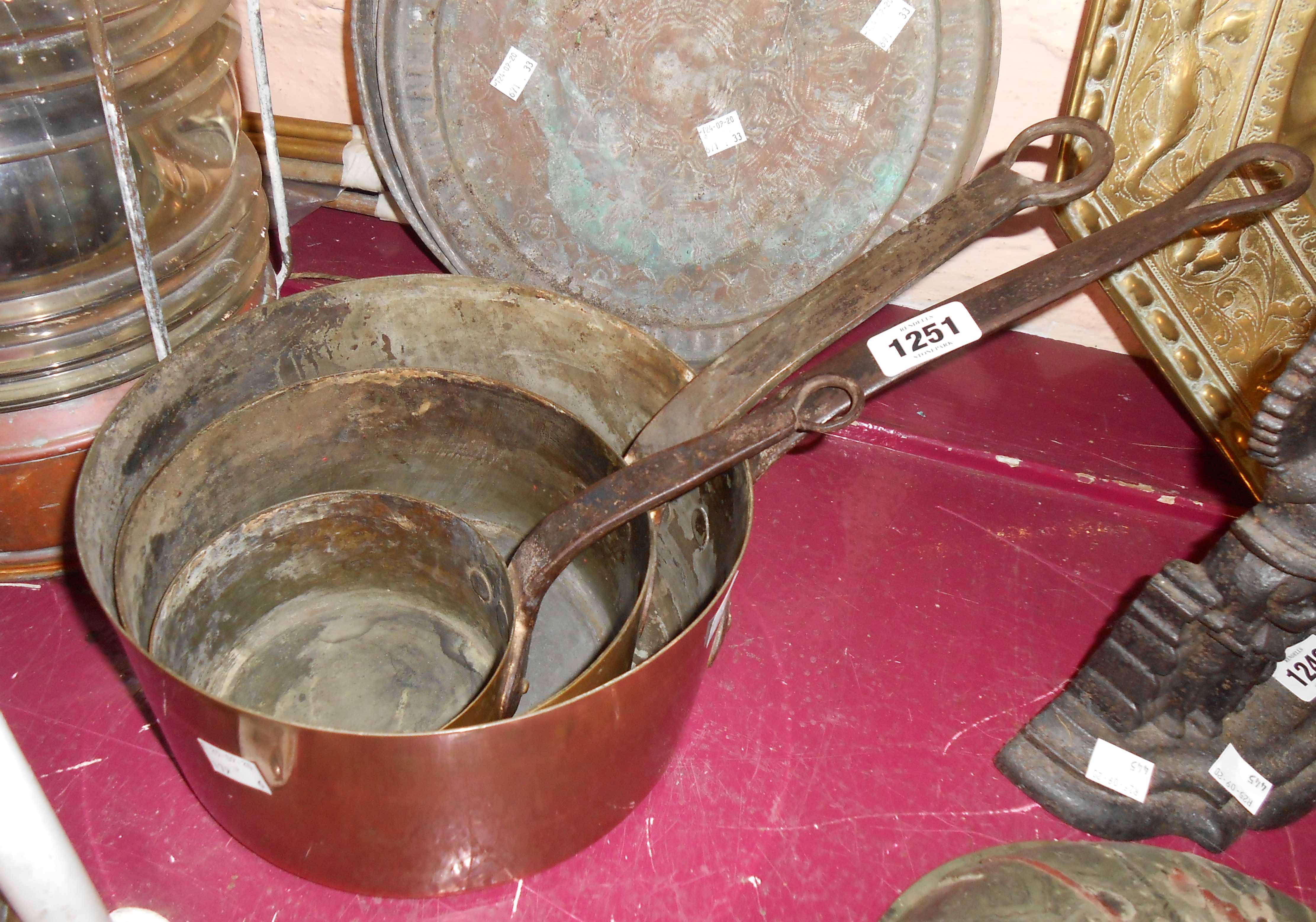 A set of three graduated antique copper saucepans with iron handles