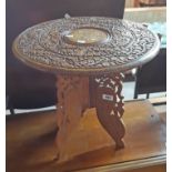 A 18" 20th Century Indian tripod table with profuse carved and inlaid decoration to top, set on a