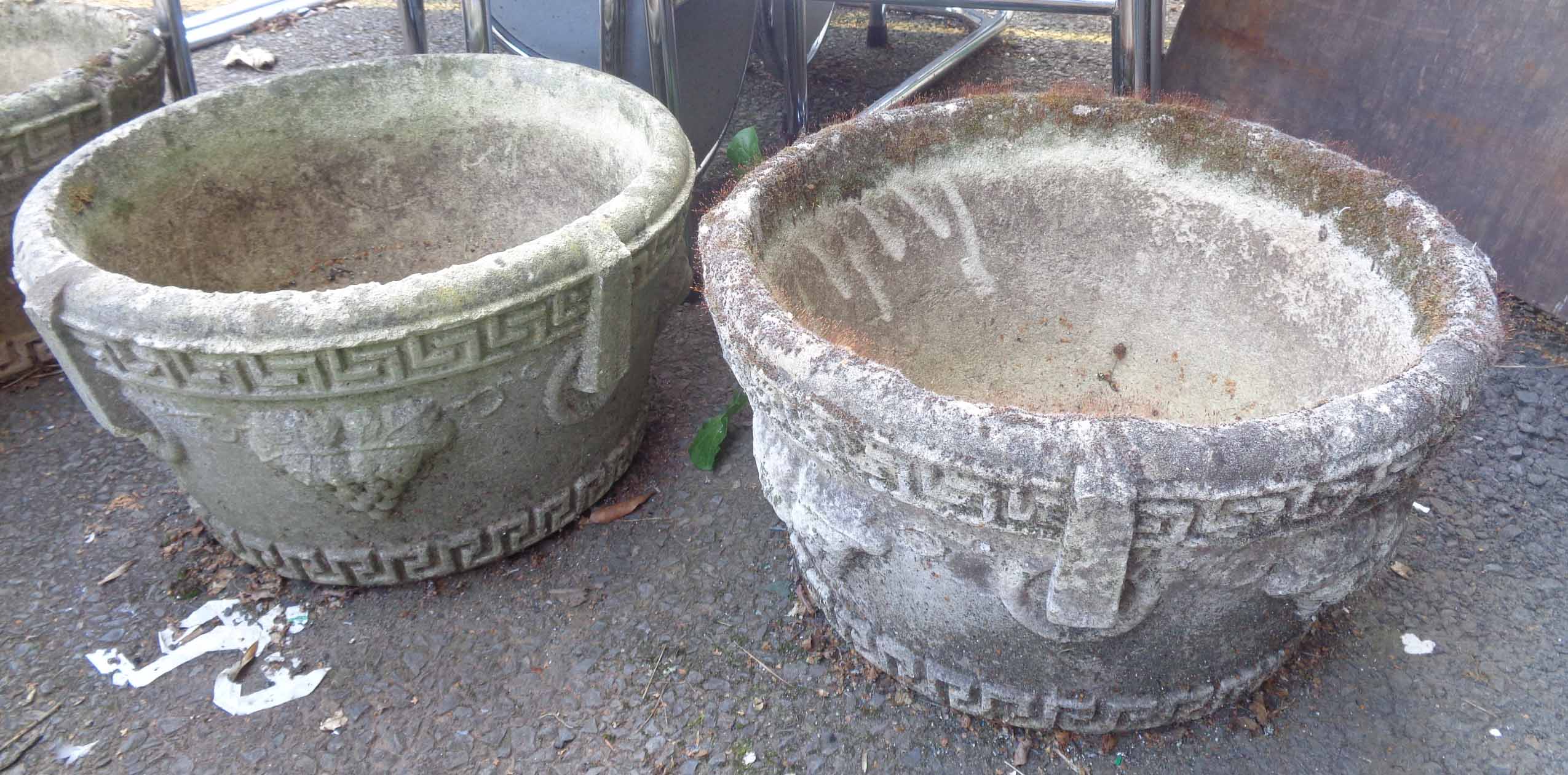 A pair of circular concrete garden planters with grapevine decoration