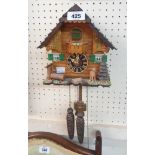 A modern German cuckoo wall clock with twin pine cone pattern weights and certificate of