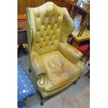 A 20th Century Georgian style wingback armchair with remains of studded leather upholstery, set on