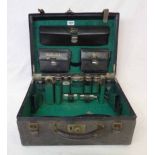 An early 20th Century leather travelling toilet case containing five original silver topped jars