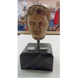 A small marble statue head in the Classical style on plinth base