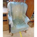 A late Victorian wingback armchair with remains of later velour upholstery, set on a fan carved