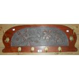 A 31" early 20th Century stained wood wall mounted coat rack with central carved perching bird on