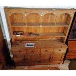 A 6' 1" modern pine two part dresser with arched and spindle decoration to plate rack over a base