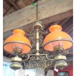 A brass twin branch hanging lamp with orange glass shades