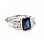 A hallmarked 750 white gold ring, set with central oblong sapphire and flanking square cut diamonds