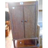 A 15 1/2" early 20th Century oak two door music cabinet with panelled sides, set on short square