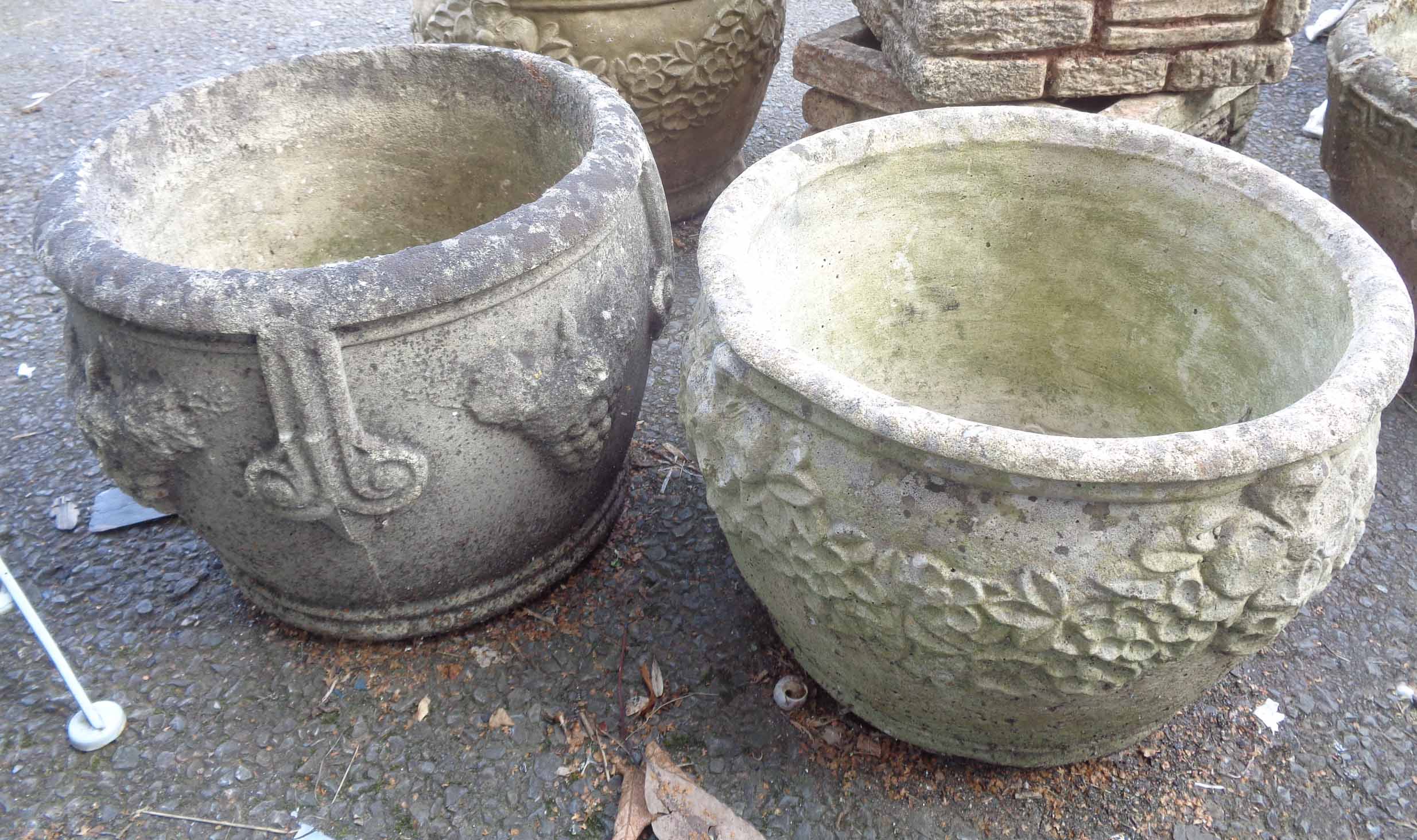 Two concrete garden planters of circular form, one with grapevine decoration, the other with