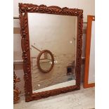 A modern carved and stained pine framed bevelled wall mirror