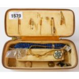 A vintage jewellery case containing yellow metal and other jewellery items including stick pins