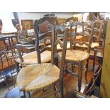 A set of eight French oak framed ladder back dining chairs with woven rush seats and moulded front