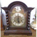 A early 20th Century stained oak break dome top cased table clock with decorative dial, flanking