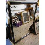 A 4' 2 1/2" high reproduction parcel gilt and ebonised framed bevelled oblong wall mirror with