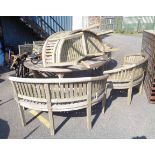 A teak patio set comprising large circular table and a set of four demi-lune bench seats