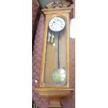 An early 20th Century polished oak cased regulator wall clock with decorative pediment, glazed door,