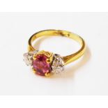 A hallmarked 750 gold ring, set with central oval pink sapphire and flanking brilliant cut diamonds