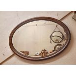 An early 20th Century oak framed bevelled oval wall mirror